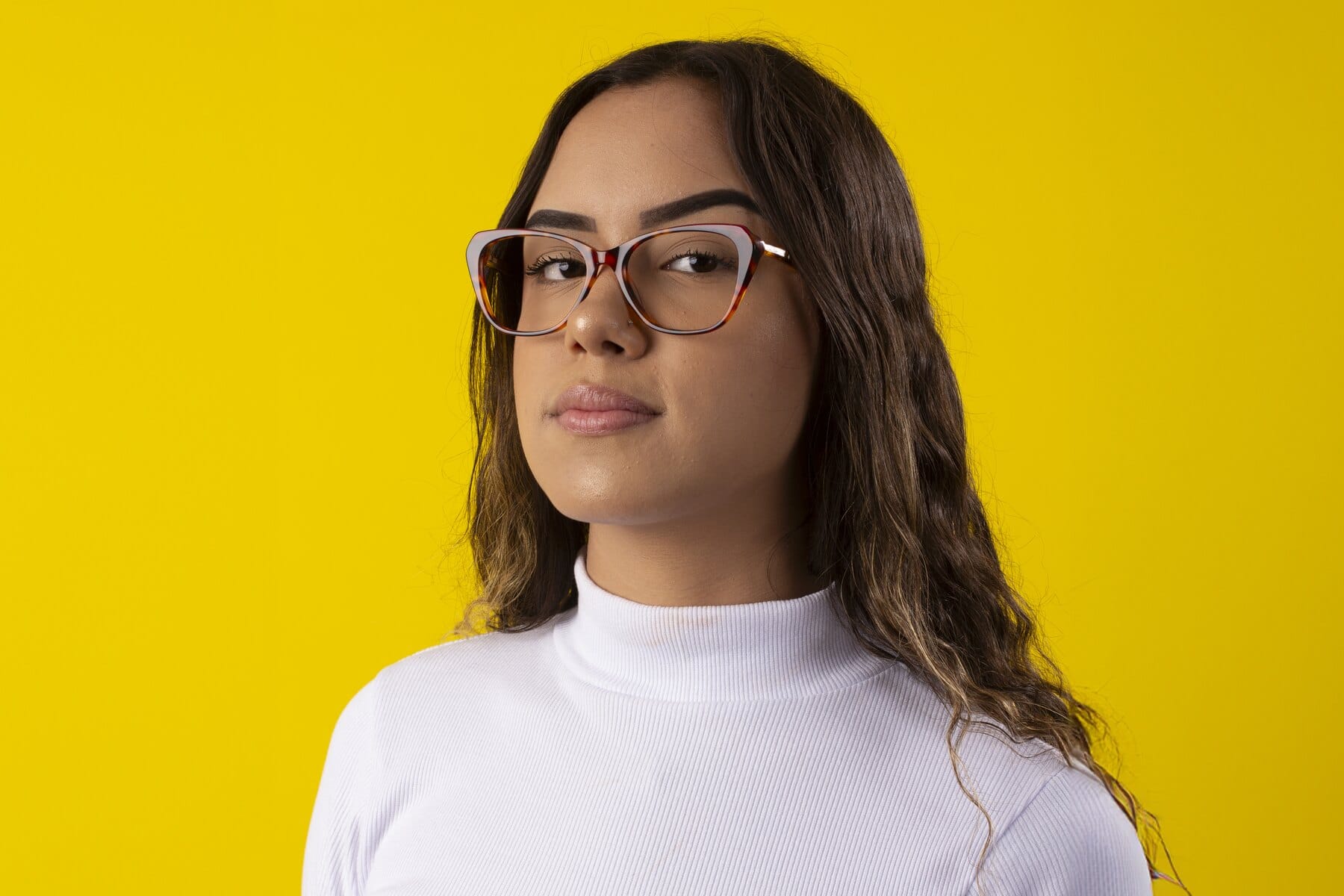 Mulher sorrindo com óculos de grau sobre fundo amarelo